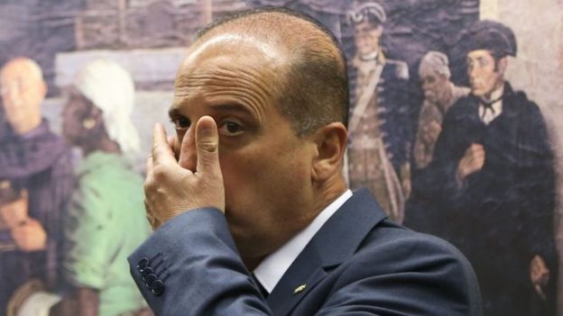 Deputado leva a mão ao rosto em frente a quadro