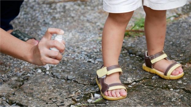 Mãe passa repelente em perna de menino