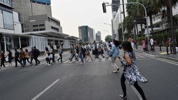 Warga menyeberang di Jalan MH Thamrin, Jakarta Pusat pada hari Minggu (04/08)