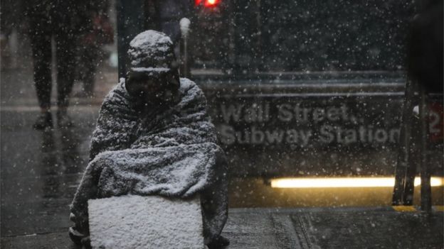 Homeless individual sits outside NYC subway station