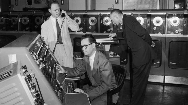 Tres hombres manejando una de las primeras computadoras.