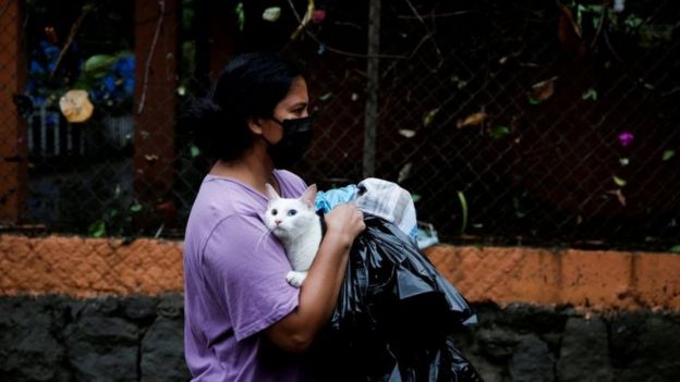 A woman wearing a face mask walks holding a cat during floods caused by Tropical Storm Amanda, in San Salvador, El Salvador May 31, 2020