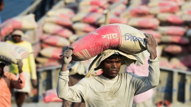 Trabajador descarga un saco de cemento de un buque cerca de Daca, febrero 2020.