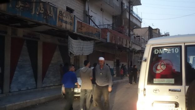 Men walk in front of closed shops in Madaya