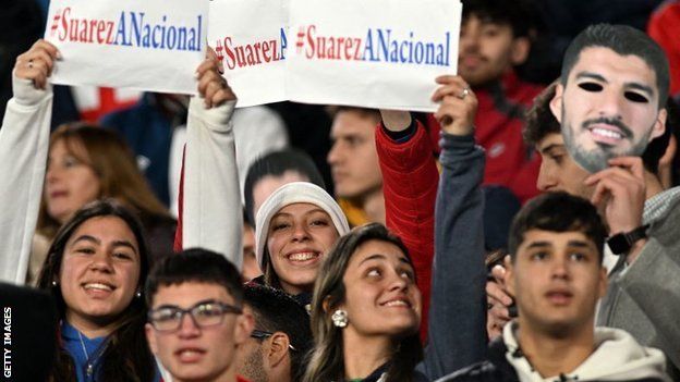 Fans hold aloft a Luis Suarez mask and banners at Nacional's game with Cerrito