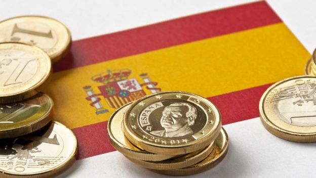 Monedas de euro sobre una bandera española.
