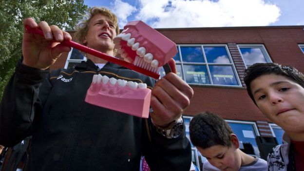 Profesor enseñando a cepillarse los dientes