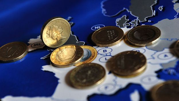 Monedas de libras y euros sobre un mapa de Europa.