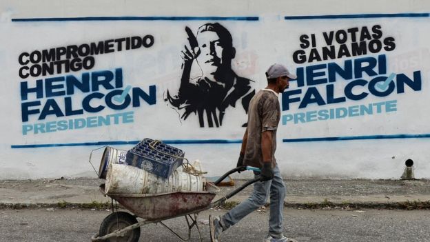 A worker passes by electoral propaganda of Venezuelan opposition presidential candidate Henri Falcon, in Barquisimeto, Venezuela