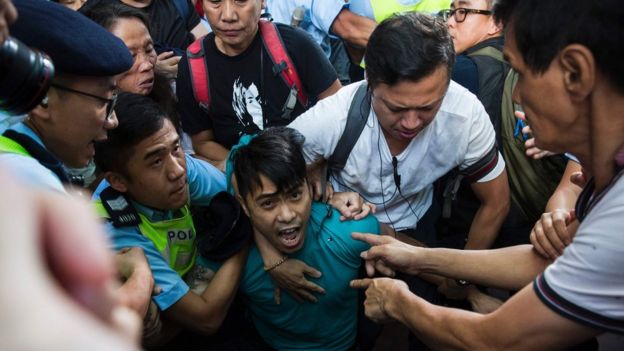 A pro-Beijing supporter is forcibly removed by police as he tries to stop a League of Social Democrats protest in Hong Kong, 1 July 2017