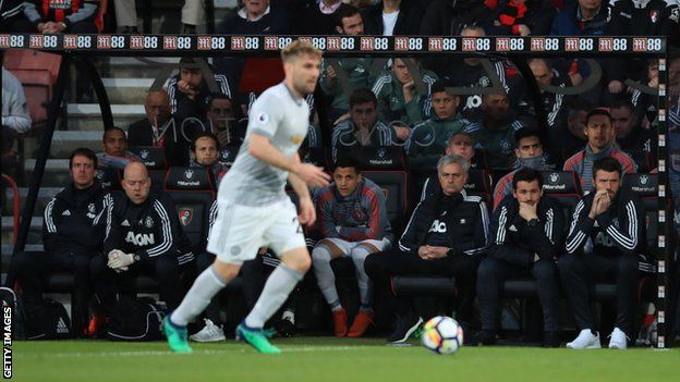 Luke Shaw plays in front of Jose Mourinho