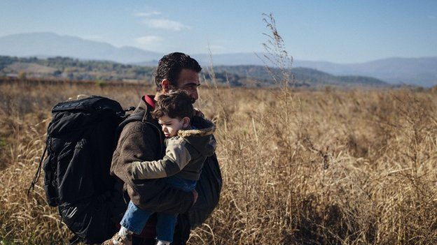 Parent carrying child on Greek border