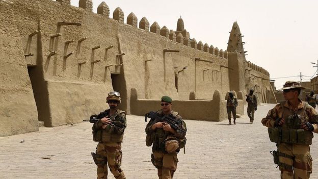 French soldiers of the 93rd Mountain Artillery Regiment and soldiers of the Malian Armed Forces patrol next to the Djingareyber Mosque on June 6, 2015 in Timbuktu