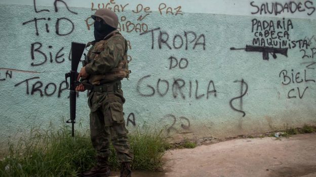 Soldado em frente a muro pichado na Vila Kennedy