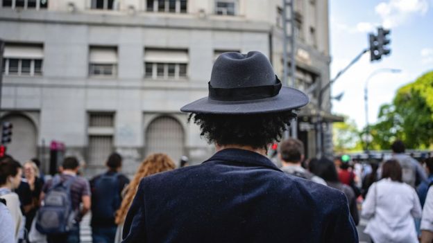 Homem com chapéu cruza rua