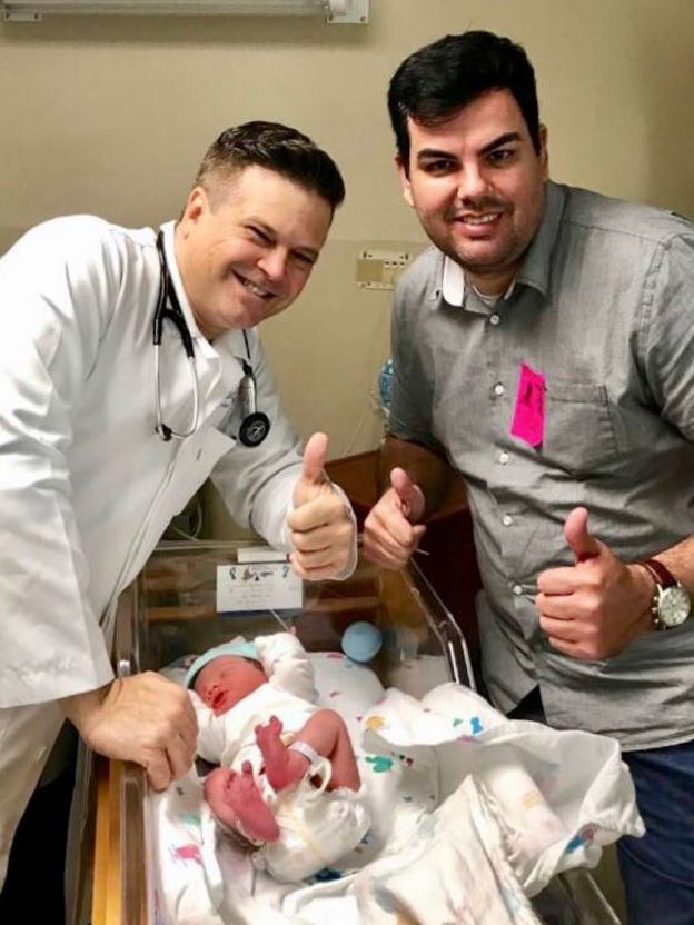 O médico Wladimir Lorentz e o brasileiro Thiago Panes ao lado de bebê recém-nascido