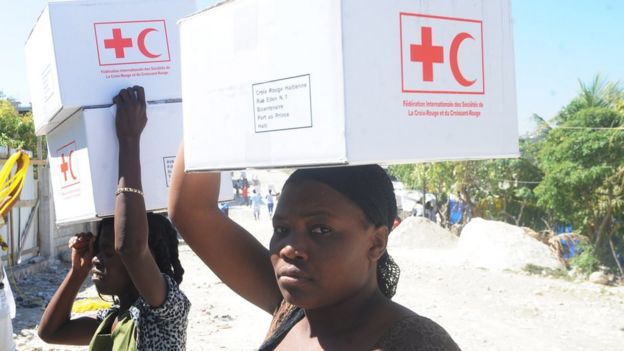 Mujeres cargan sobre sus hombros cajas que contienen kits anti cólera.