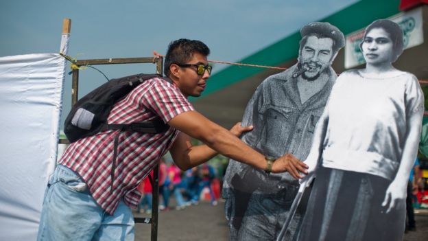 Un joven sostiene imágenes de Prudencia Ayala junto a la de Ernesto 'Che' Guevara.
