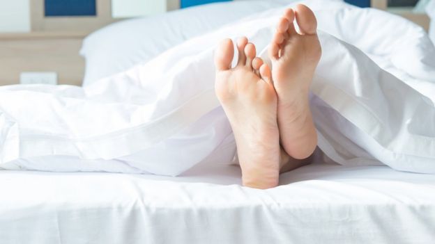 Persona durmiendo con los pies descubiertos.