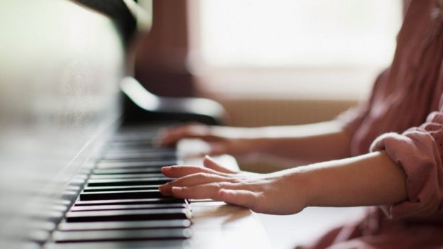 Close up of girl's hands on piano - stock photo