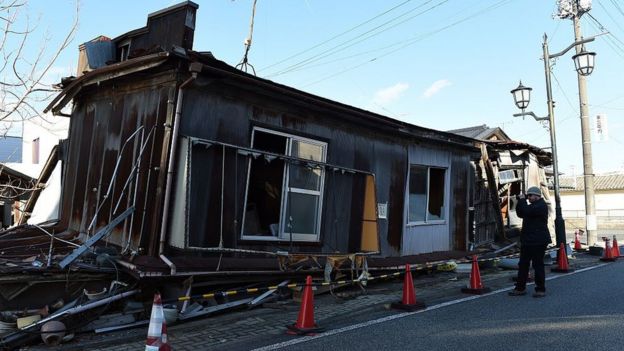 Turista na frente de casa destruida