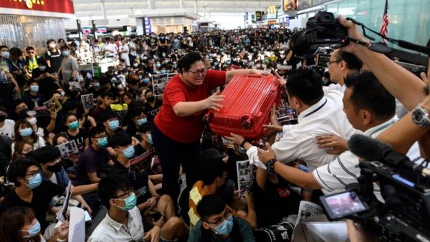 A tourist (C) gives her luggage to security guards as she tries to enter the departures gate