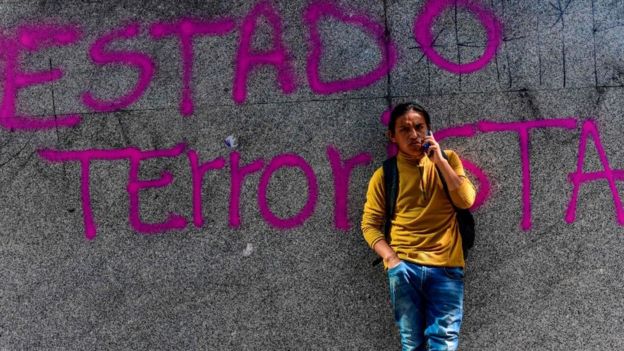 Una pintada en una pared dice "Estado Terrorista"