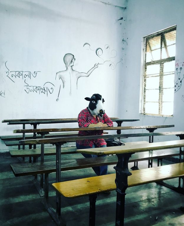 A woman with a cow mask in a college classroom