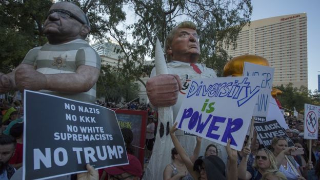 Large inflated figures of Sheriff Joe Arpaio and President Trump are seen above ant-Trump protesters outside the Phoenix Convention Center