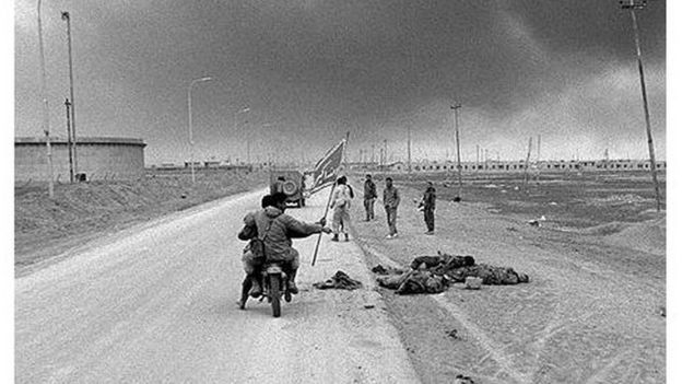 جنود ايرانيون على دراجة نارية يمرون بجانب جثث جنود عراقيين