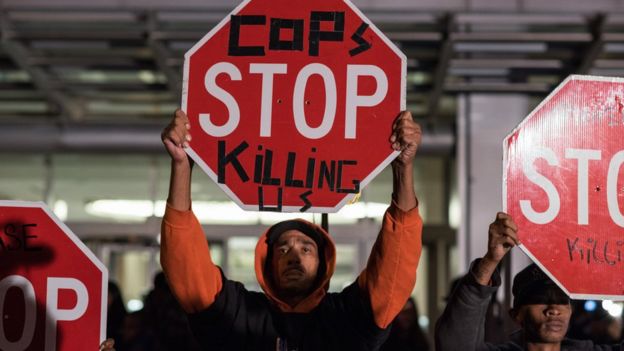 Protesters hold "cops stop killing us" signs