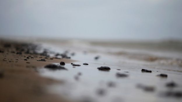 Foco em pedaços de óleo na areia