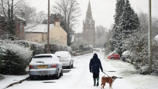 A man walks his dog in the snow in Muston, Leicestershire
