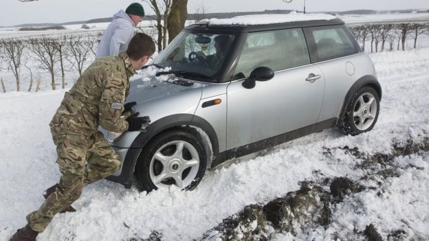 Man pushes car out of snow