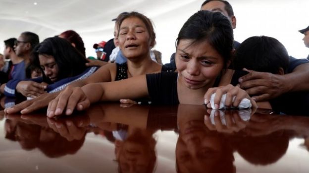 Personas lloran junto a un ataúd