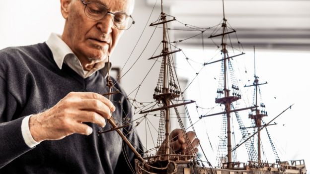 Un hombre de edad armando un modelo de barco