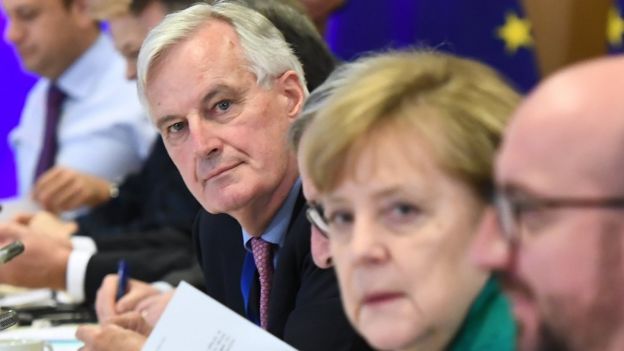 Chief Brexit negotiator Michel Barnier, centre, looks at the camera, as does German Chancellor Angela Merkel (in slightly soft focus)
