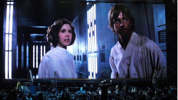 Actress Carrie Fisher's Princess Leia Organa character and actor Mark Hamill's Luke Skywalker character from 'Star Wars Episode IV: A New Hope' are shown on screen while musicians perform during 'Star Wars: In Concert' at the Orleans Arena May 29, 2010 in Las Vegas, Nevada.