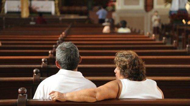 People sit in a pew in a cathedral in El Salvador