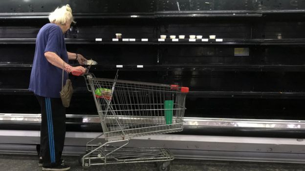 Una señora en un supermercado ante una cámara vacía.