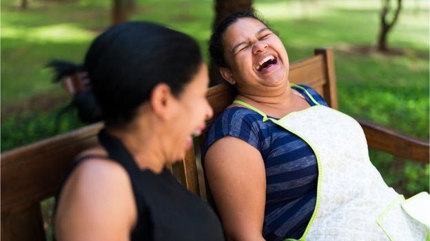 mulheres riem em um banco de parque