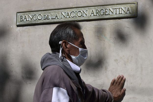 Un hombre con tapabocas hace cola frente al Banco de la Nación Argentina.