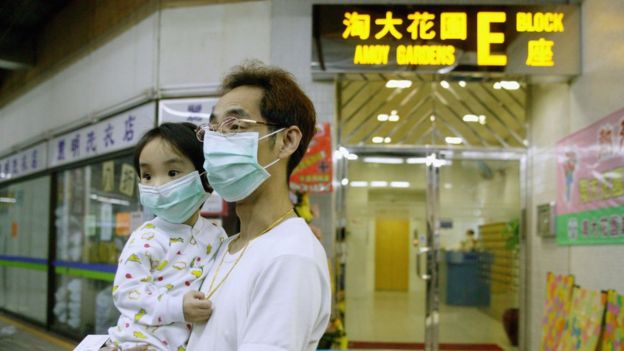 A man holds child outside of Amoy Gardens block in Hong Kong in 2003