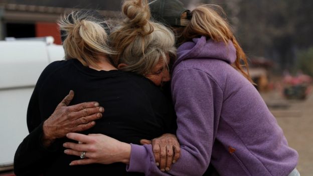 Cathy Fallon (C) who stayed behind to tend to her horses during the Camp Fire, embraces Shawna De Long (L) and April Smith who brought supplies for the horses in Paradise, California, U.S. November 11, 2018.