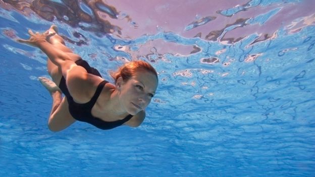 Mujer bajo el agua con los ojos abiertos.