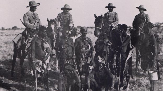 Prisioneiros herero acorrentados, na companhia de soldados alemães montados