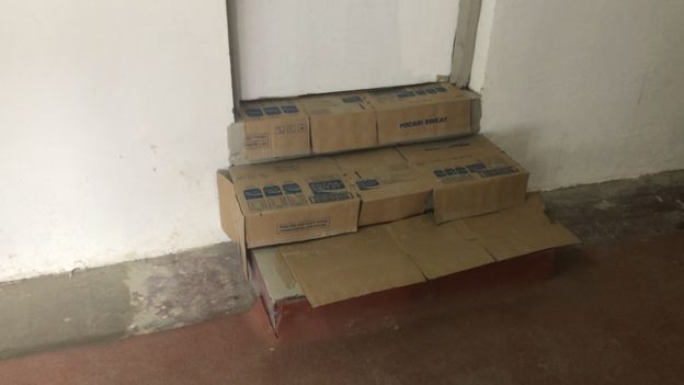 Cardboard boxes cover the stairs leading to a door
