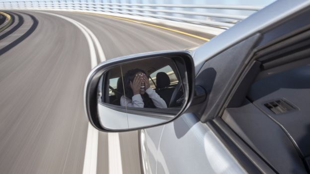 Mujer tapándose los ojos en un coche que circula a gran velocidad.