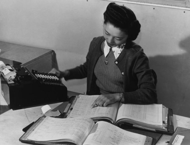 Contadora Teruko Kiyomura actualizando manualmente varios libros de contabilidad en 1943.