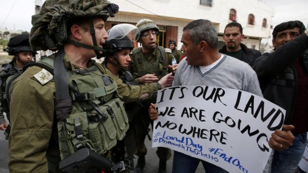 A Palestinian argues with an Israeli soldier during a protest to mark